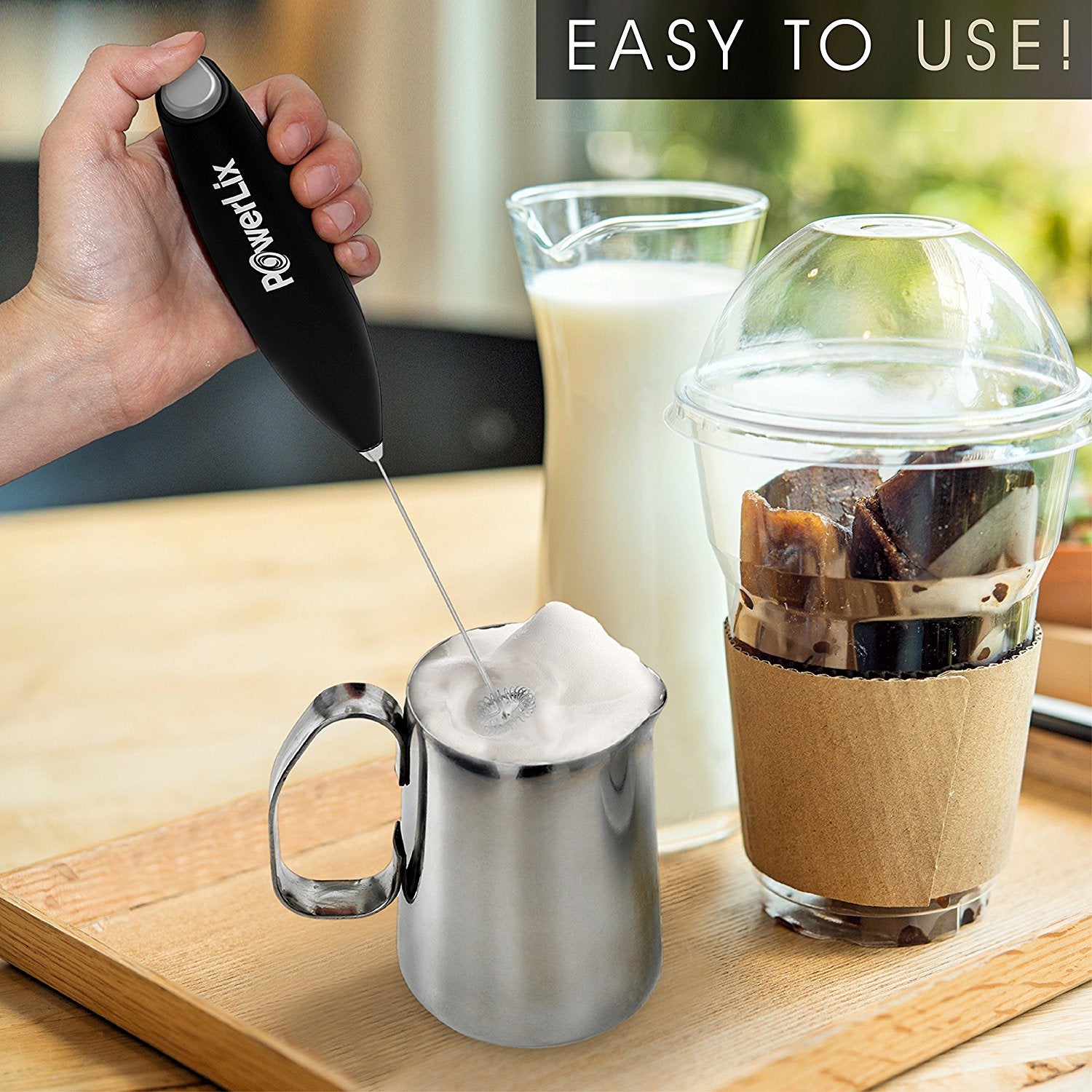 Powerlix milk frother in use to foam milk in the milk pitcher. There is a glass of milk and iced coffee cup behind it. The text above reads, "Easy to use."